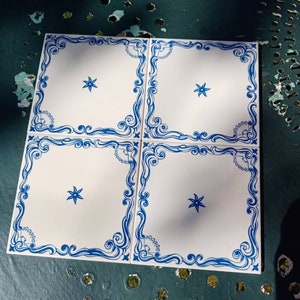 Pode incluir: Quatro azulejos de cerâmica branca com bordas decorativas azuis e uma estrela azul no centro de cada azulejo.