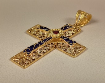 May include: Gold-colored filigree cross pendant with blue enamel accents and a red gemstone center. The cross features intricate openwork designs and a decorative bail for a necklace chain.
