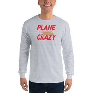 May include: A gray long-sleeve t-shirt with the text "PLANE CRAZY" in red lettering. A small brown airplane graphic is centered above the text.