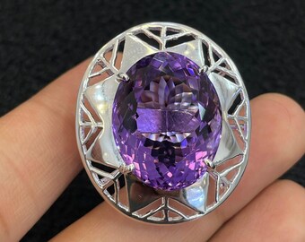 May include: A silver ring with a large, oval-shaped amethyst gemstone set in a geometric design.