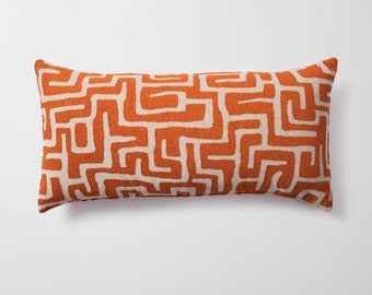 May include: Orange and white patterned lumbar pillow with a geometric design.