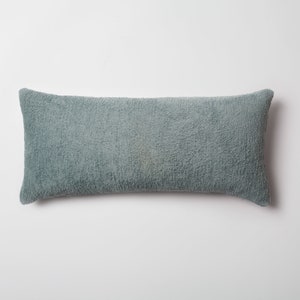 May include: A long, rectangular, light blue throw pillow with a soft, fuzzy texture.