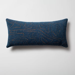 Peut inclure: Un coussin de canapé bleu et marron avec une surface texturée.