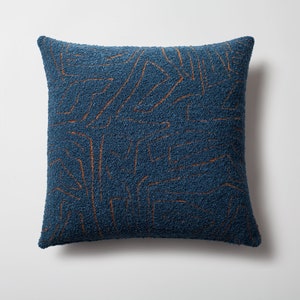 May include: Blue throw pillow with a brown geometric pattern. The pillow is made of a textured fabric.