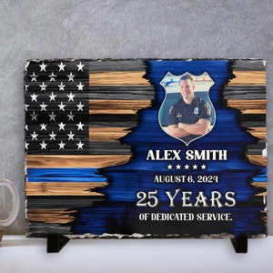 May include: A blue and brown wooden slate plaque with a thin blue line flag design. The plaque features a photo of a police officer, the name "Alex Smith", the date "August 6, 2024", and the text "25 Years of Dedicated Service."