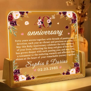 May include: A 40th anniversary illuminated sign with a wooden frame and floral design. The sign reads "40th anniversary" and "Sophia & Darius 02.23.1985".