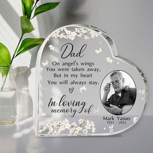 Peut inclure: Un mémorial en verre en forme de cœur avec une photo d'un homme et un motif floral. Le texte dit "Papa, Sur les ailes des anges Tu as été emporté, Mais dans mon cœur Tu resteras toujours. ♡ En souvenir affectueux de Mark Yasuo 1951 - 2023"