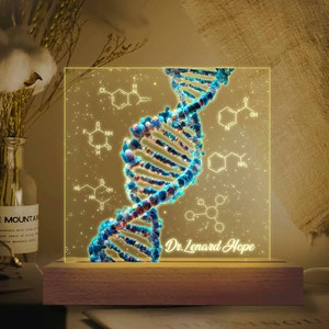 May include: A DNA helix design night light with a wooden base. The light is a square shape with a glowing blue and white double helix design and chemical structures. The text "Dr. Lenard Hope" is at the bottom.