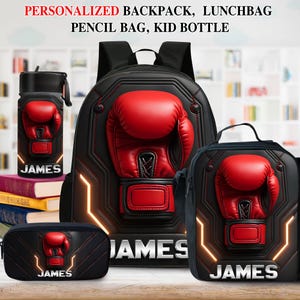 Könnte beinhalten: Ein Set aus schwarzem Rucksack, Lunchpaket, Federmäppchen und Trinkflasche. Jeder Artikel hat ein rotes Boxhandschuh-Design und den Namen "JAMES" in Weiß. Das Set ist für Kinder.