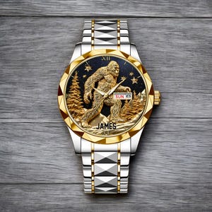 May include: A silver and gold wristwatch with a detailed Bigfoot design on the face. The watch features a gold bezel, a black dial with a Bigfoot figure, trees, and stars. The watch band is silver with geometric accents. The name "JAMES" is printed on the watch face.