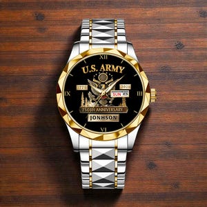 May include: A silver and gold wristwatch with a black face. The watch face features the text "U.S. ARMY", an eagle emblem, and the text "250TH ANNIVERSARY". The watch band is silver with gold accents. The name "JONHSON" is printed on the watch face.