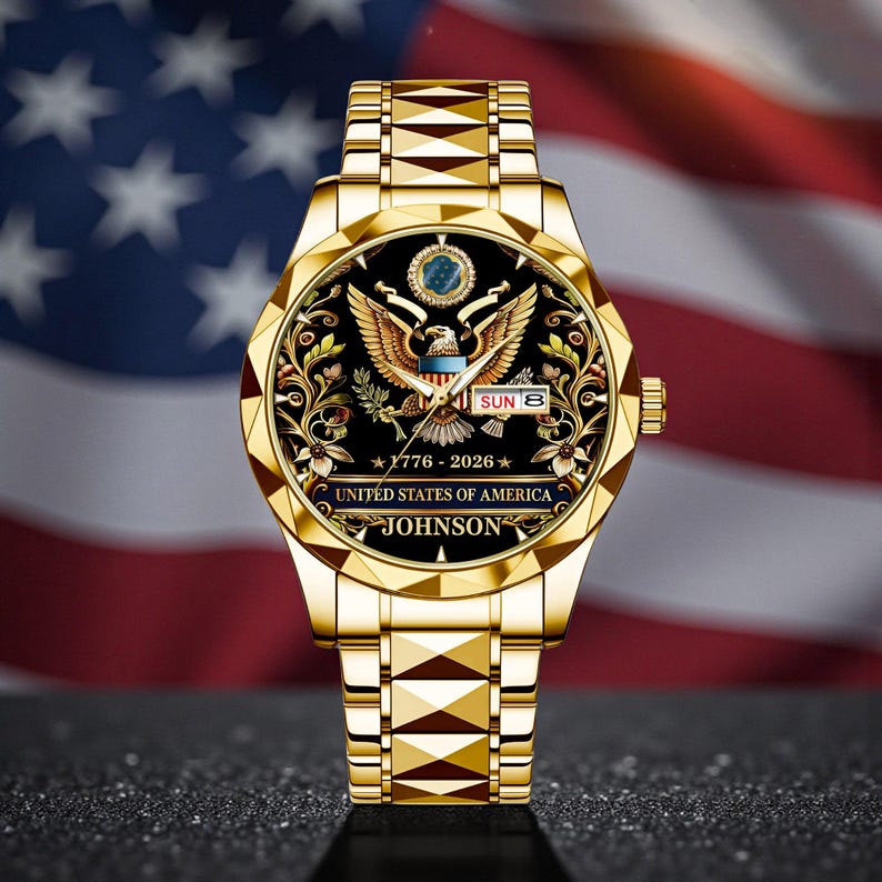 May include: A gold-toned wristwatch with a black face featuring the United States of America's emblem, the date, and the name "JOHNSON." The watch has a gold band and is set against a backdrop of the American flag.