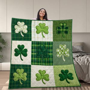 May include: A green and white patchwork quilt featuring various shamrock designs. The quilt has a quilted pattern and is made of different fabrics, including plaid and dotted patterns. The shamrocks are in shades of green.
