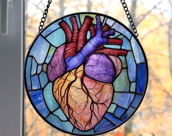 May include: A stained glass window hanging with a colorful anatomical heart design. The heart is depicted in shades of red, purple, and orange with visible veins and chambers. The background is a mosaic of blue and green glass.