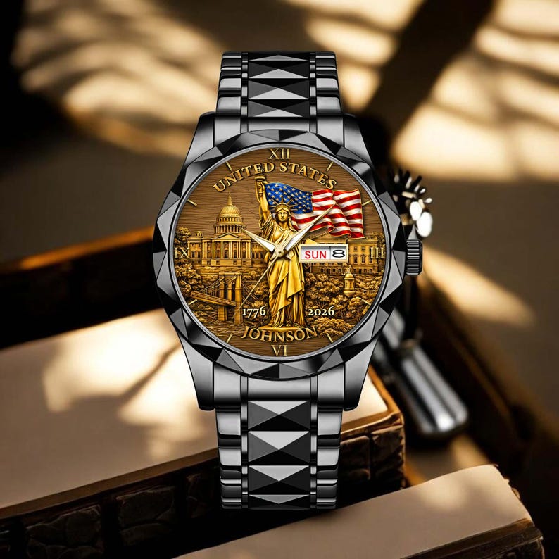 Peut inclure: Une montre-bracelet argent&eacute;e avec un cadran d&eacute;taill&eacute; repr&eacute;sentant la Statue de la Libert&eacute;, le drapeau am&eacute;ricain et le Capitole des &Eacute;tats-Unis. Le cadran affiche &eacute;galement la date. Le bracelet est &agrave; maillons g&eacute;om&eacute;triques.