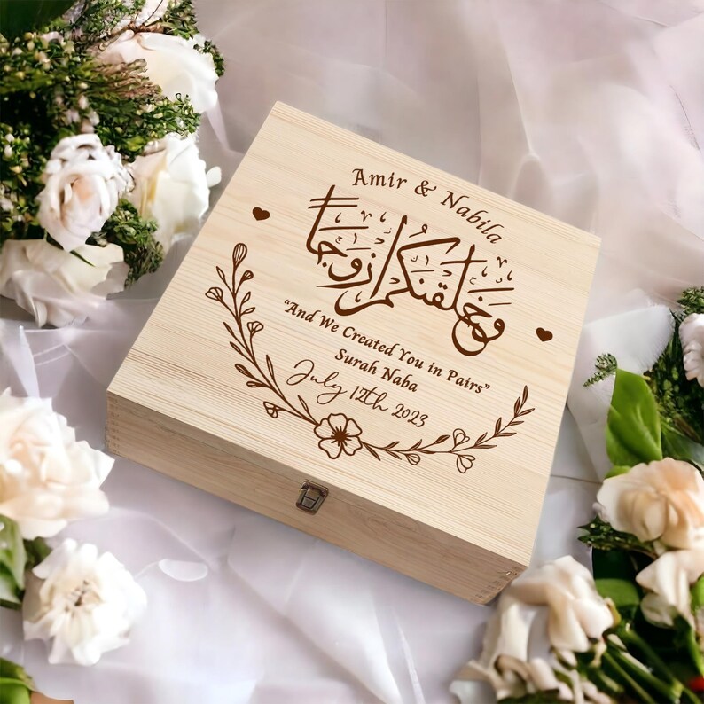 May include: A wooden box with a floral design and the text "Amir & Nabila" and "And We Created You in Pairs" Surah Naba July 12th 2023" engraved on the lid.