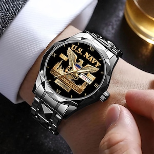 May include: A silver-toned wristwatch with a black face featuring the text "U.S. NAVY" and a golden eagle emblem. The watch commemorates the "250th Anniversary" with the years 1775 and 2025. The watch band is made of linked metal.