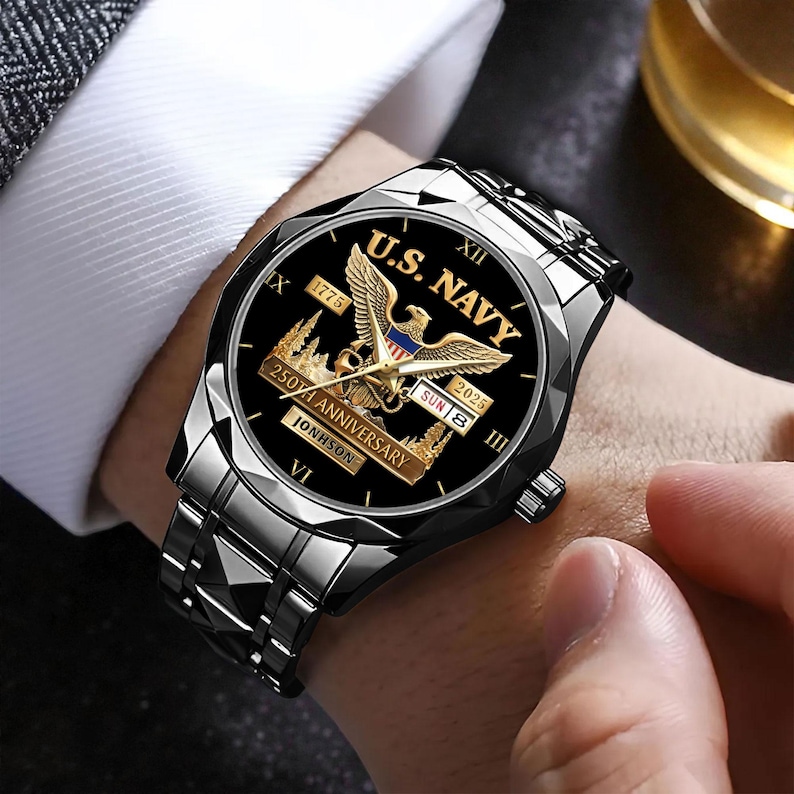 May include: A silver-toned wristwatch with a black face featuring the text "U.S. NAVY" and a golden eagle emblem. The watch commemorates the "250th Anniversary" with the years 1775 and 2025. The watch band is made of linked metal.
