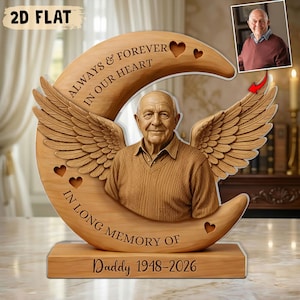 Könnte beinhalten: Gedenktafel aus Holz mit einem geschnitzten Bild eines Mannes mit Engelsflügeln, vor einem Halbmond. Die Tafel enthält den Text "Always & Forever In Our Heart" und "In Long Memory Of Daddy 1948-2026."