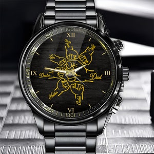 May include: Black wristwatch with a black face and gold Roman numeral hour markers. The watch face features a design of five fists with names written on each fist: Lion, Dexter, Holden, Caileb, and Dad. The names are written in gold.