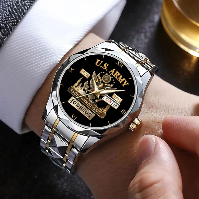May include: A silver and gold wristwatch with a black face featuring the text "U.S. ARMY" and "250TH ANNIVERSARY". The watch has a date display and a silver and gold band. The watch is on a wrist.