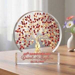 Könnte beinhalten: Ein durchsichtiges Jubiläumandenken aus Glas mit einem Baumdesign, verziert mit roten und goldenen blattförmigen Details. Auf der Basis steht "40th Anniversary", die Namen "David & Sophia" und ein Datum.