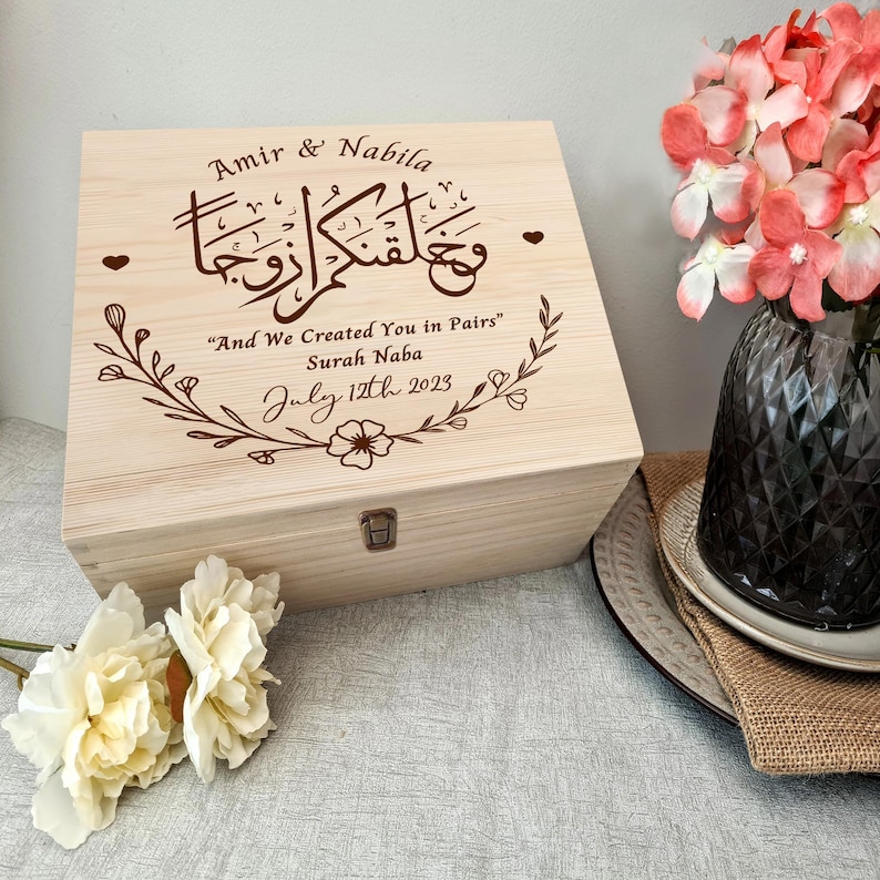 May include: A wooden box with a floral design and the inscription "Amir & Nabila" and the Arabic text "وَخَلَقْنَاكُمْ أَزْوَاجًا"  "And We Created You in Pairs" Surah Naba July 12th 2023.