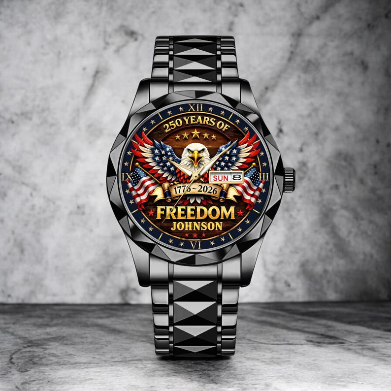 Puede incluir: Reloj de pulsera plateado con esfera detallada. La esfera presenta un &aacute;guila con las alas extendidas, banderas americanas y el texto "250 YEARS OF FREEDOM JOHNSON 1776-2026". La correa es de metal.