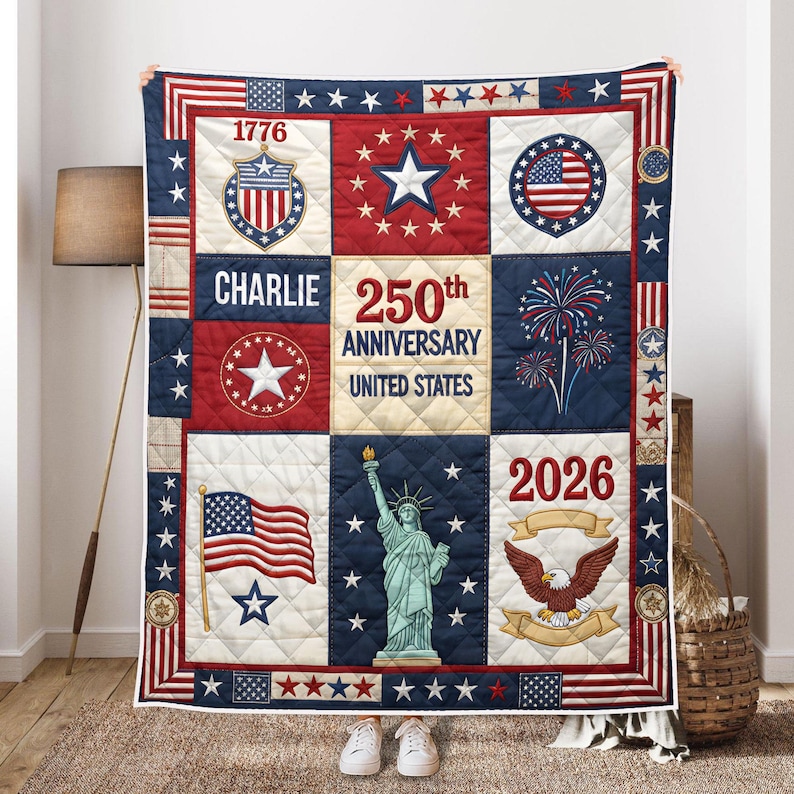 Pu&ograve; includere: Una trapunta patriottica con un design patchwork nei colori rosso, bianco e blu. La trapunta include immagini della bandiera americana, della Statua della Libert&agrave; e di un'aquila, insieme al testo "1776", "Charlie", "250th Anniversary United States" e "2026".