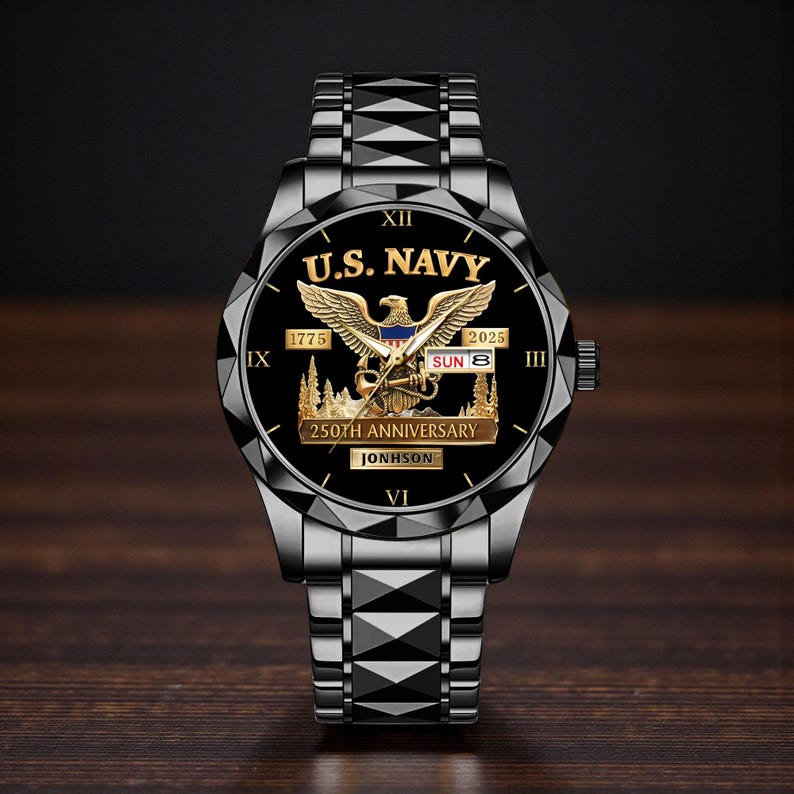 May include: A black wristwatch with a metallic band and a black face. The watch face features the text "U.S. NAVY" above a golden eagle emblem. The watch also displays the date and the text "250TH ANNIVERSARY".