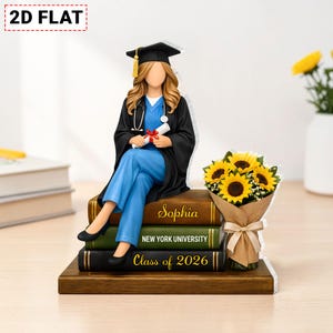 May include: A graduation figurine of a person in a cap and gown, holding a diploma, seated on books. The books are inscribed with "Sophia", "New York University", and "Class of 2026". A bouquet of sunflowers is next to the figurine.