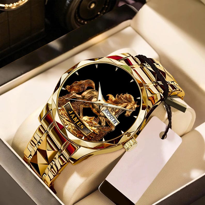 May include: A gold-toned wristwatch with a black face featuring a detailed relief of a horse and rider. The watch has a gold band and a date display. The word "JAMES" is visible on the watch face.