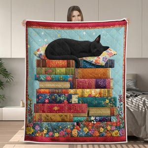 May include: A quilted blanket featuring a black cat sleeping atop a stack of colorful books. The books have floral and patterned covers. The blanket has a light blue background with stars and a red border with a floral design.