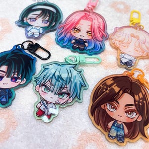 May include: A collection of anime-style character keychains. Each keychain features a different character with unique hair colors and outfits. The keychains are made of clear acrylic and have metal clasps or plastic clips for attachment.
