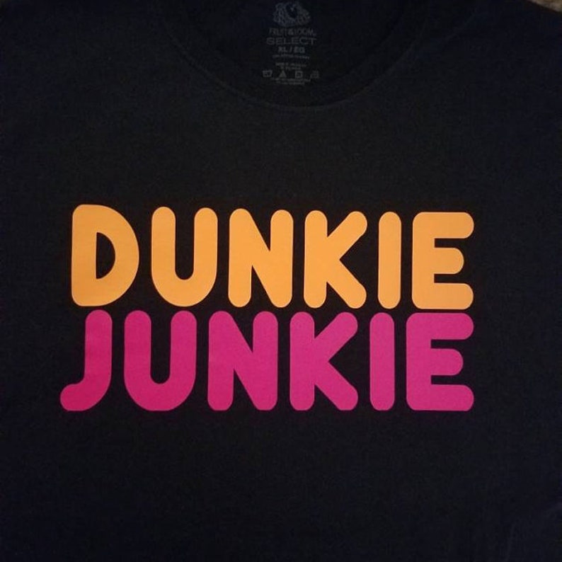 K&ouml;nnte beinhalten: Schwarzes T-Shirt mit den Worten "Dunkie Junkie" in orangefarbenen und rosafarbenen Buchstaben.