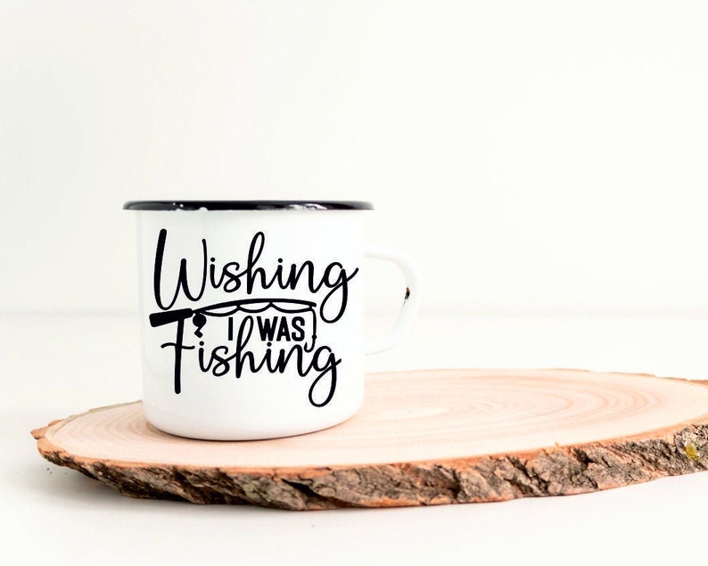 May include: White enamel mug with a black rim and a black graphic that says "Wishing I Was Fishing" with a fishing rod and line.