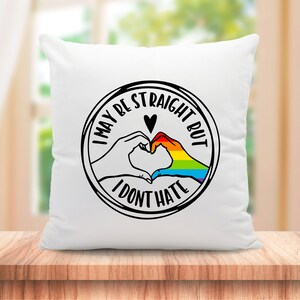Pu&ograve; includere: Cuscino bianco con una grafica in bianco e nero di due mani che formano un cuore con un arcobaleno al suo interno. Il testo intorno al cuore dice "Potrei essere etero, ma non odio".