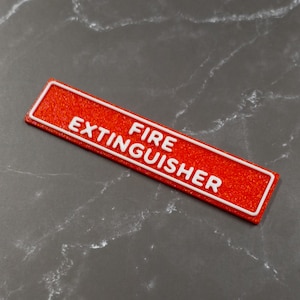 May include: A rectangular, red sign with the words "FIRE EXTINGUISHER" in white, outlined in white. The sign has a textured surface and is likely used for safety purposes.