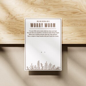 May include: Handmade Worry Worm card with a brown border and white background. The card has a message that reads "I'm your little worry worm, hold me close and tight. You can take me anywhere, I'm here to make things bright. When you're feeling worried, give me a big squeeze. Take a couple of deep breaths and you'll soon be at ease."