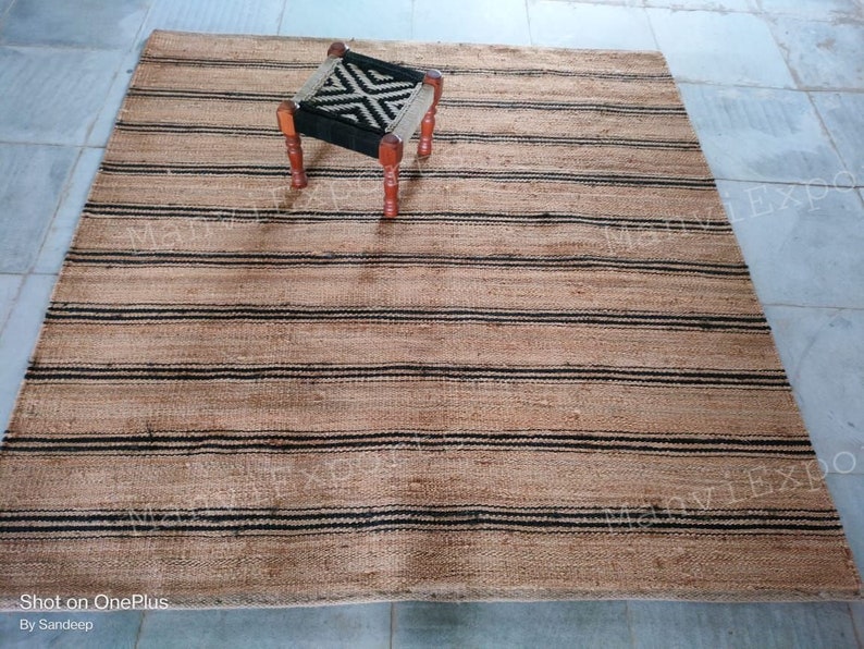 May include: A natural fiber rug with black and brown stripes. The rug is made of jute and is perfect for adding a touch of natural beauty to any room.