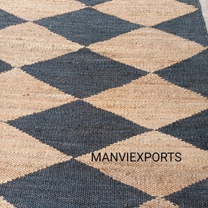May include: A black and beige jute rug with a diamond pattern. The rug is woven with natural fibers and has a rustic look. The text "MANVIEXPORTS" is visible in the lower right corner of the rug.