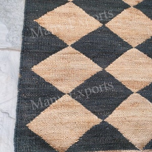 May include: A black and beige woven rug with a diamond pattern. The rug is made of natural fibers and has a rustic look.