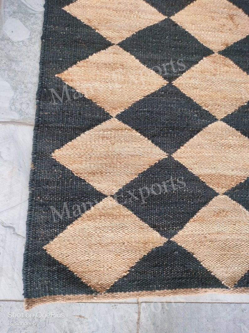 May include: A black and beige woven rug with a diamond pattern. The rug is made of natural fibers and has a rustic look.