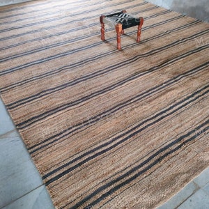 May include: A natural fiber rug with black and brown stripes. The rug is made of jute and is perfect for adding a touch of natural beauty to any room.
