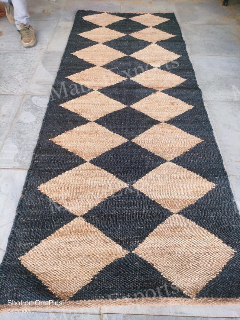 May include: A black and beige checkered jute rug. The rug is made of natural fibers and has a woven texture.