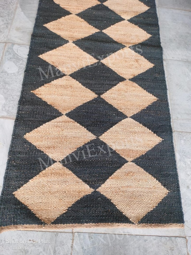 May include: A black and beige checkered rug made of woven jute. The rug has a diamond pattern and is perfect for adding a touch of natural texture to any room.