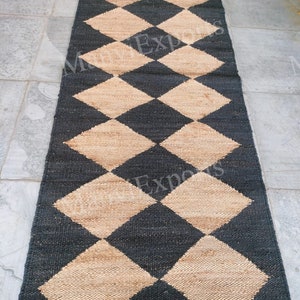 May include: A black and tan jute rug with a diamond pattern. The rug is made of natural fibers and has a rustic look.