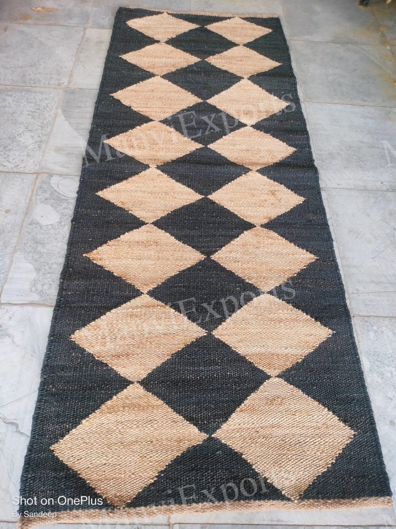 May include: A black and tan jute rug with a diamond pattern. The rug is made of natural fibers and has a rustic look.