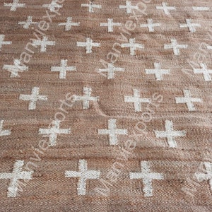 May include: A brown jute rug with a white cross pattern. The rug has a natural, rustic look and feel.