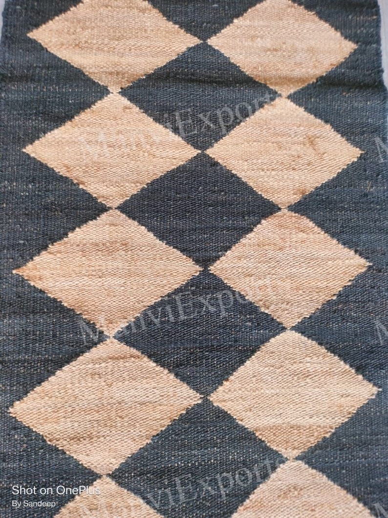 May include: A black and beige woven rug with a diamond pattern. The rug is made of natural fibers and has a rustic look.